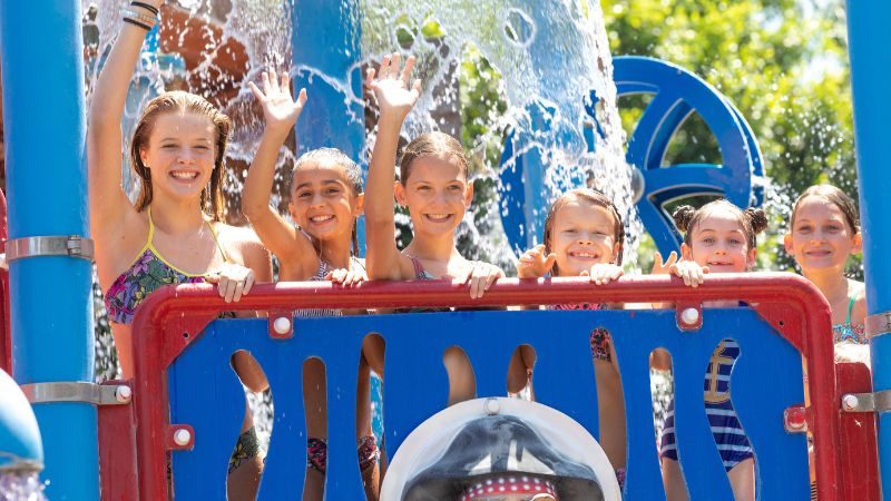 Kids waving on water play area inside Buccaneer Cove at Castle Park